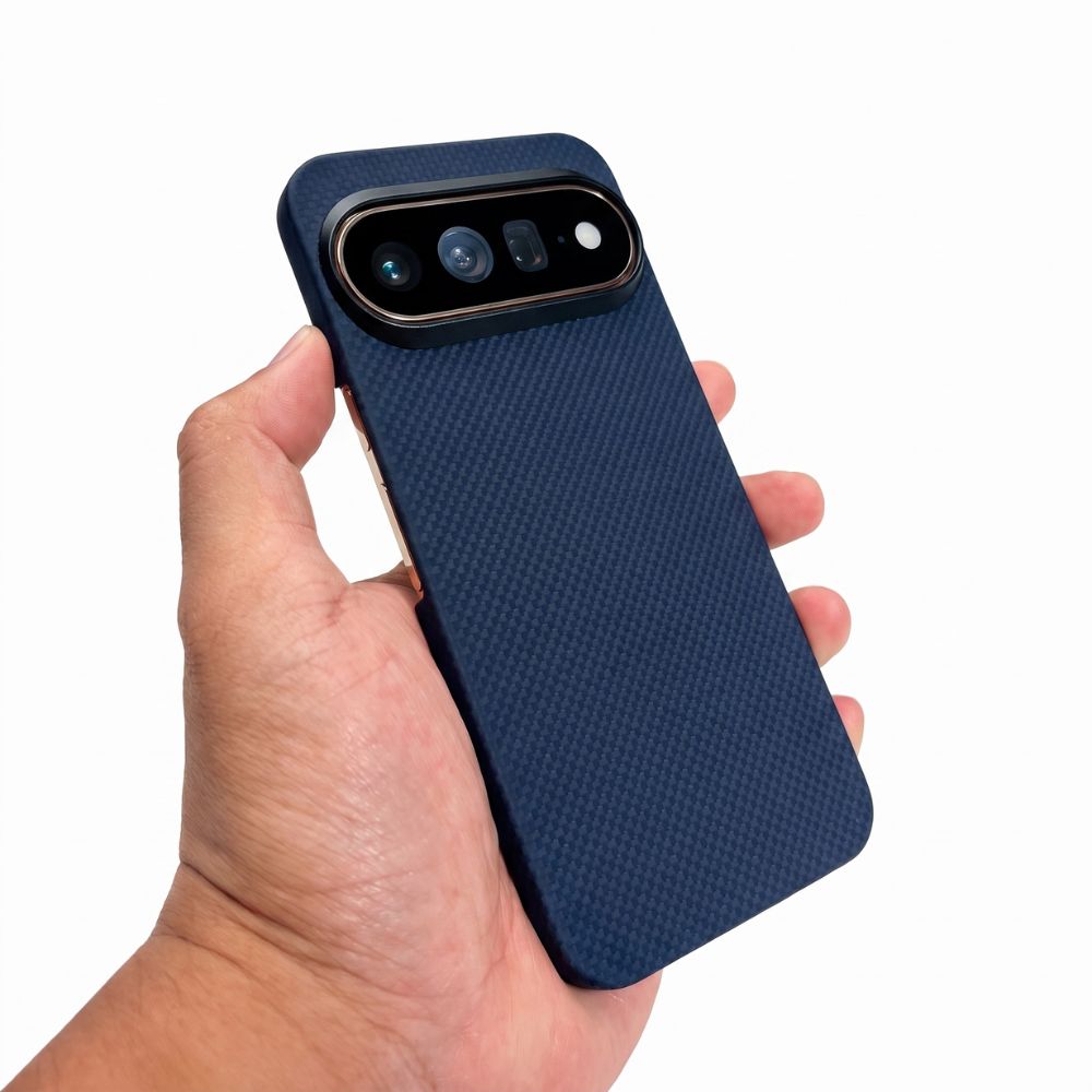 Hand holding navy blue slim Pixel 11 Pro aramid fiber protective case, woven textured back cover, white background