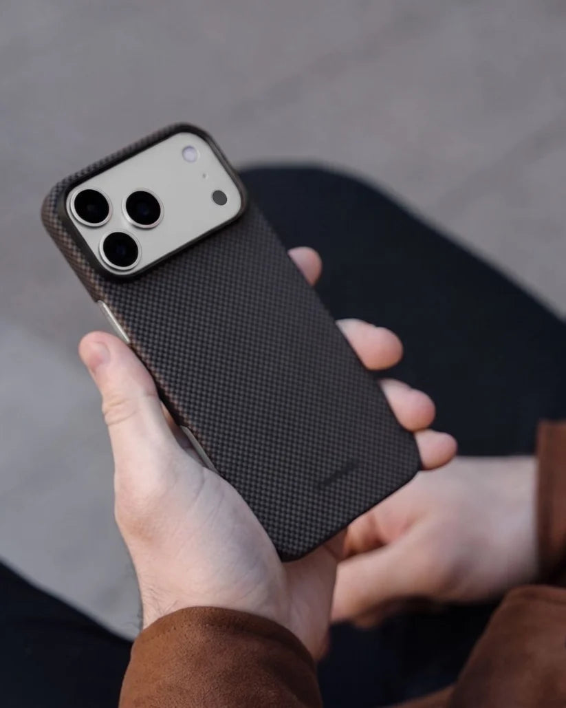 Hand holding Thinborne brown checkered iPhone 18 Pro Max aramid fiber case, outdoor lifestyle grip photo