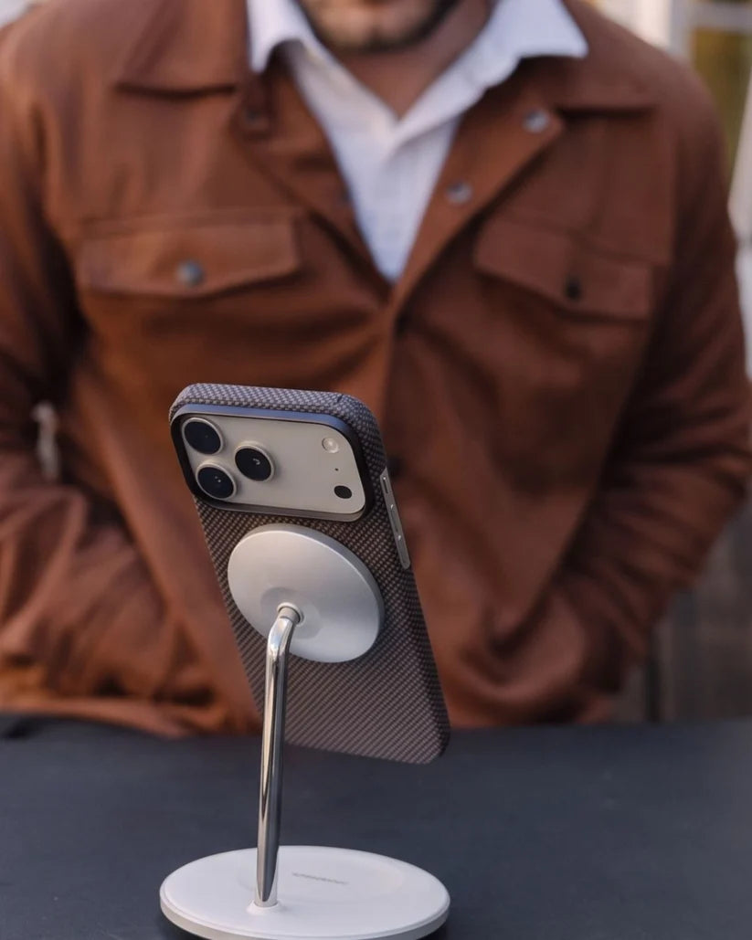 Man using Thinborne brown checkered iPhone 18 Pro Max aramid case on MagSafe desk stand, outdoor lifestyle shot