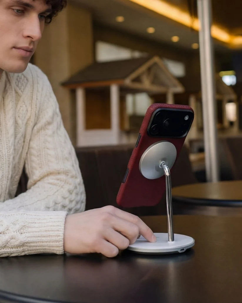 Man using crimson red Thinborne iPhone 18 Pro Max Case on MagSafe desk stand, outdoor cafe lifestyle shot