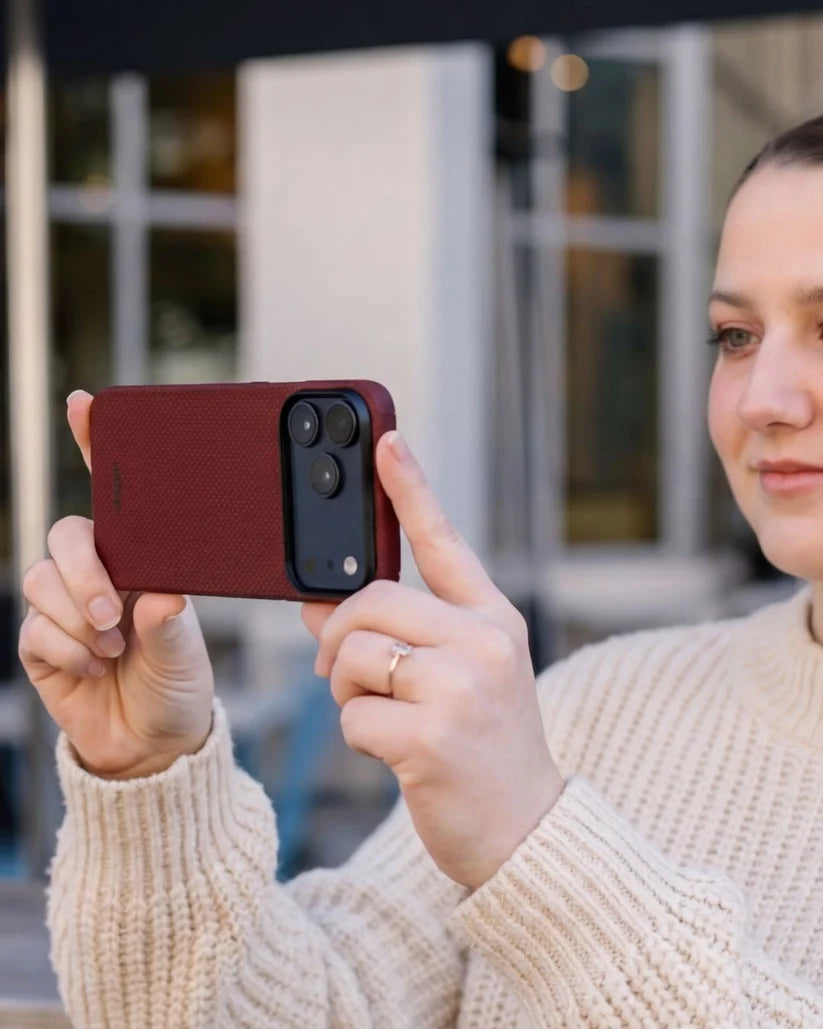 Woman holding crimson red Thinborne iPhone 18 Pro Max aramid fiber case, outdoor lifestyle photo taking shot