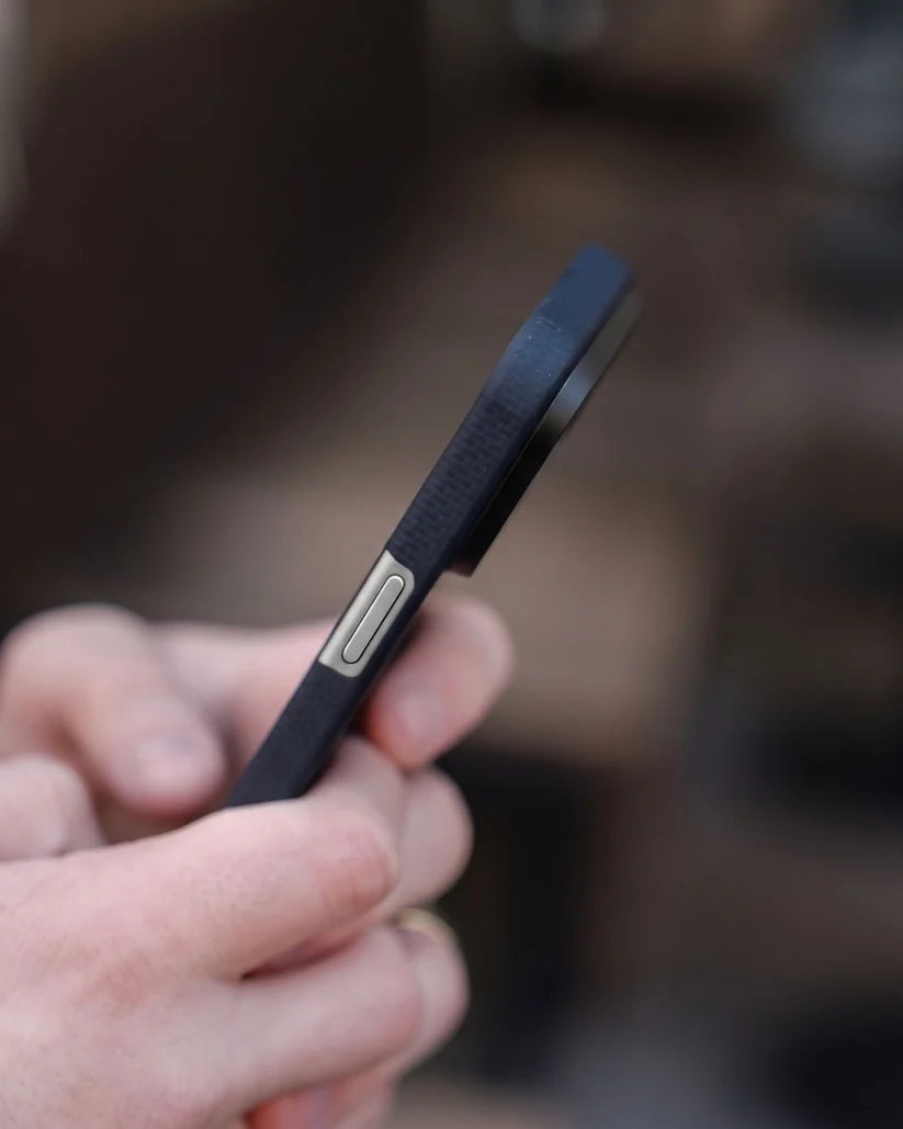 Closeup side profile of Thinborne navy iPhone 18 Pro Max aramid fiber case, showing slim edge and metal volume button